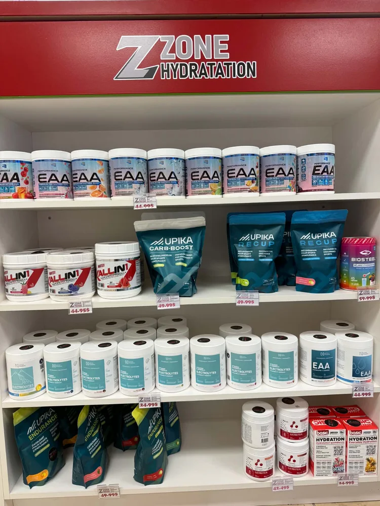 Des pots EAA disposés sur les tablettes du rayon des suppléments sportifs.